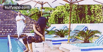 a woman is sitting on a diving board next to a pool .