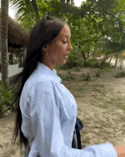 a woman with long dark hair is wearing a white shirt and a black belt .