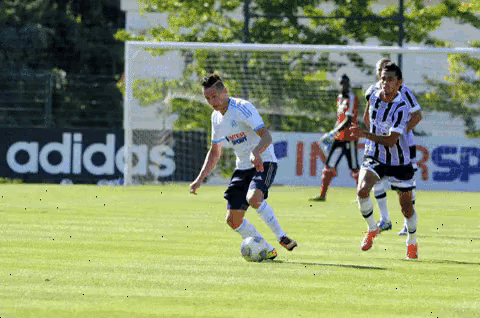 a soccer game is being played in front of a sign that says adidas