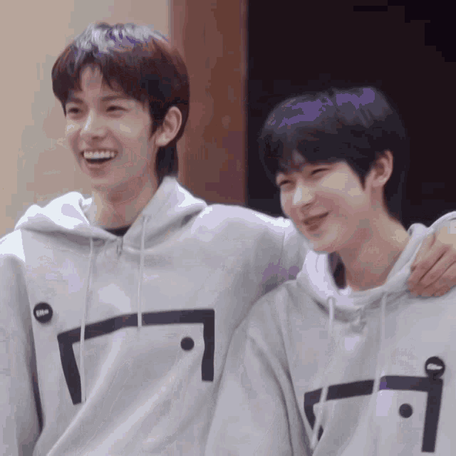 two young men wearing hoodies are standing next to each other .