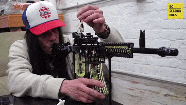a man wearing a red white and blue trucker hat is working on a rifle
