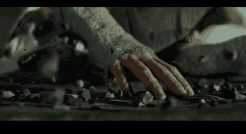 a person 's hand is reaching out towards a pile of rocks on the ground .