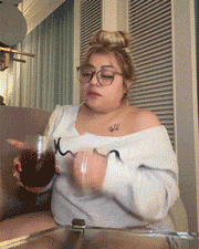 a woman wearing glasses is sitting on a couch and holding a glass of wine
