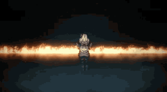 a person is standing in front of a line of fire in the dark