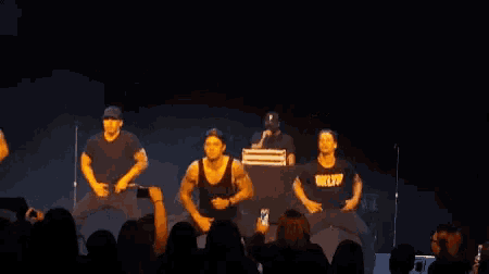 a group of men are dancing on stage in front of a crowd