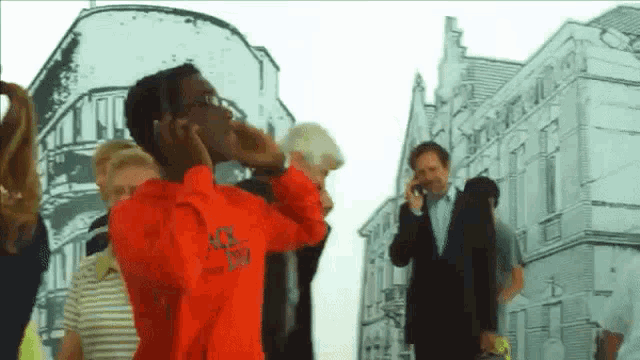 a man wearing a red sweatshirt that says stussy stands in front of a crowd