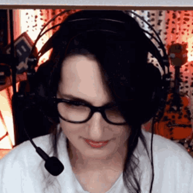 a woman wearing glasses and headphones looks at the camera