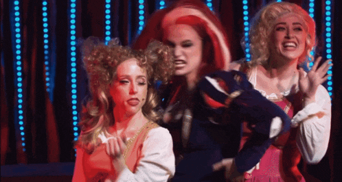 a group of women are dancing on a stage with blue lights in the background
