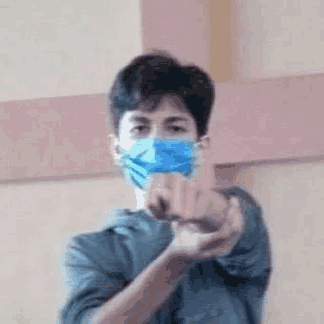 a man wearing a blue mask is making a heart with his hands .