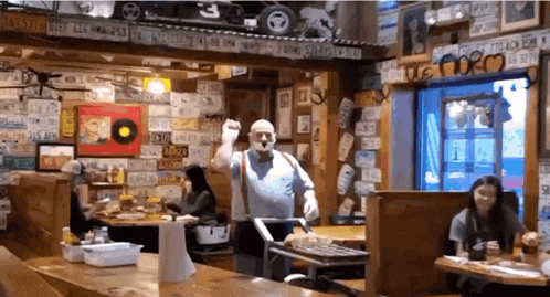 a man is dancing in a restaurant with many license plates on the wall .