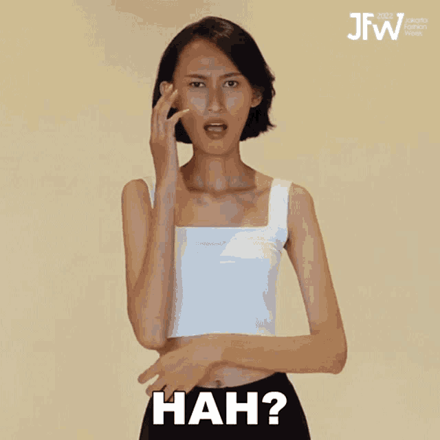 a woman wearing a white tank top is making a funny face and the word hah is above her