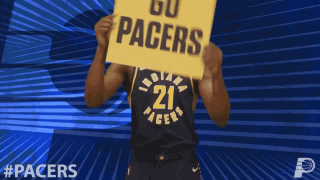 a basketball player holds a sign that says go pacers