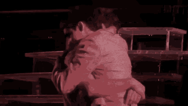 a man in a white shirt is hugging another man in a pink shirt