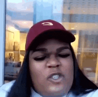 the woman is wearing a red hat and making a funny face .