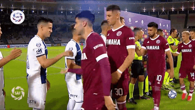 a group of soccer players wearing yamaha jerseys are shaking hands