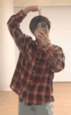a man in a plaid shirt is taking a picture of himself with his phone