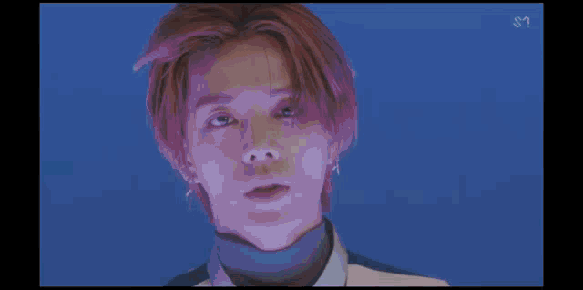 a close up of a person 's face with red hair and a blue background .