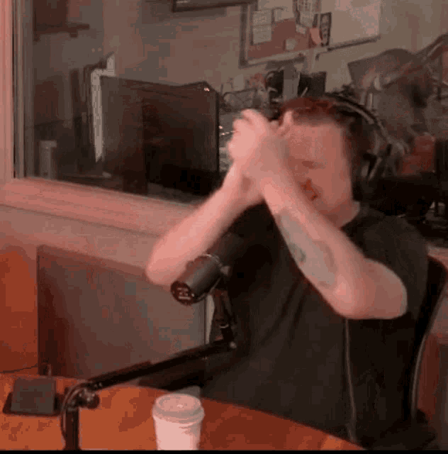 a man wearing headphones is sitting in front of a microphone in front of a window