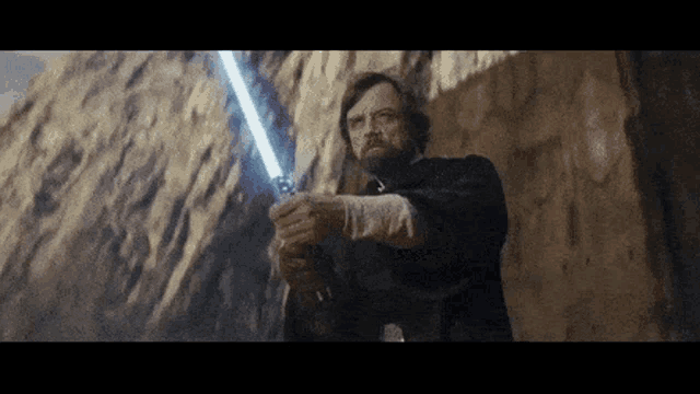 a man with a beard is holding a light saber in his hand .