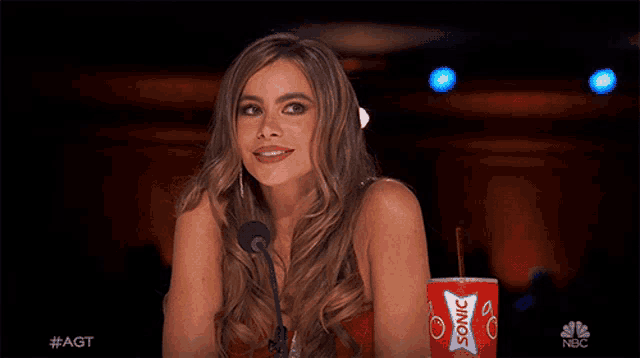 a woman sitting in front of a microphone next to a red cup that says sonic