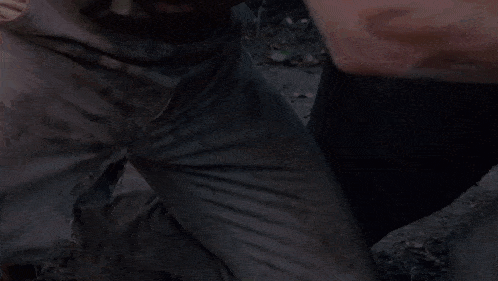 a man is laying on the ground in the woods while a woman runs towards him