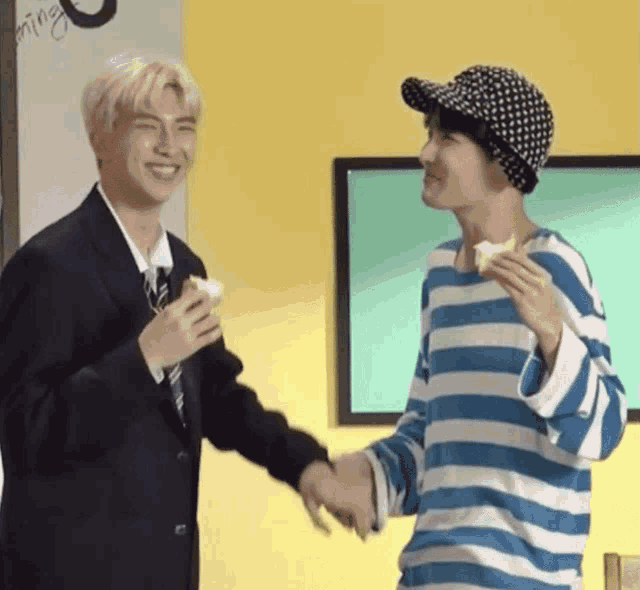 two men are shaking hands and one is holding a piece of bread