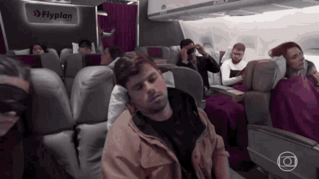 a man is sleeping on an airplane with a sign that says flyplan