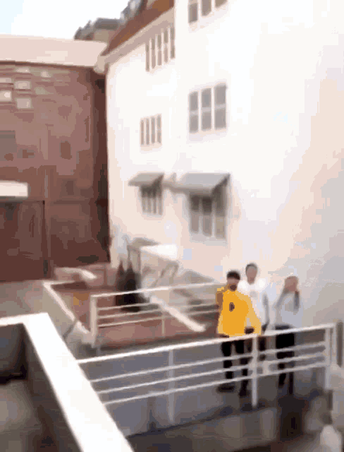 a man in a yellow shirt is standing on a balcony with other people