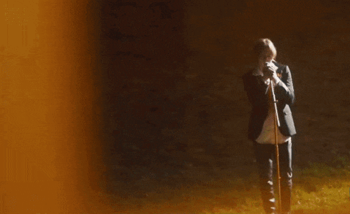 a man in a suit singing into a microphone while holding a guitar