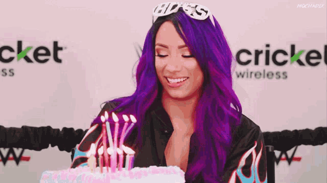 a woman with purple hair is holding a birthday cake with candles .