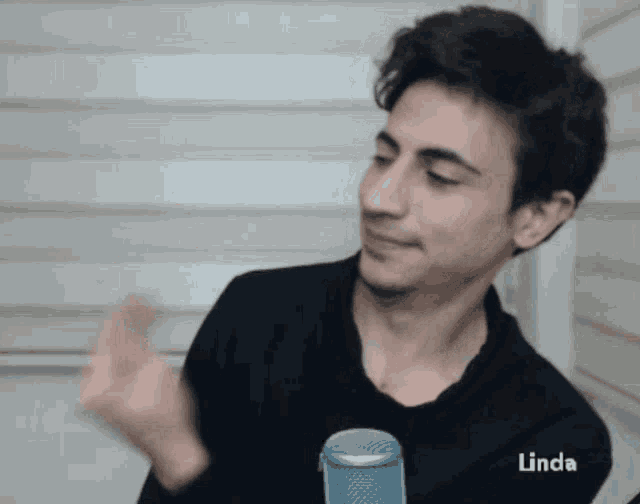 a young man in a black shirt stands in front of a microphone with linda written on the bottom