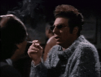 a man in a sweater is smoking a cigarette with the nbc logo in the corner