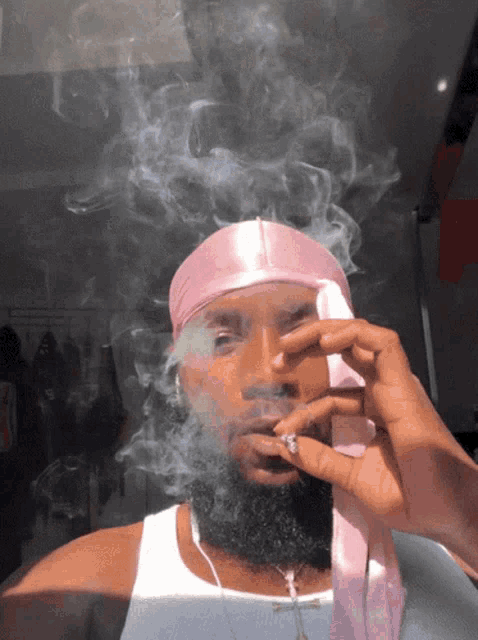 a man wearing a pink head scarf smoking a cigarette
