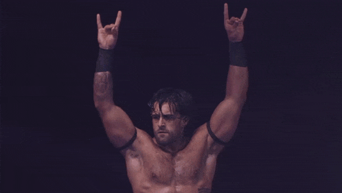 a man without a shirt is standing in the dark with his arms outstretched