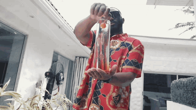 a man in a red shirt is holding a bottle of vodka in his hand