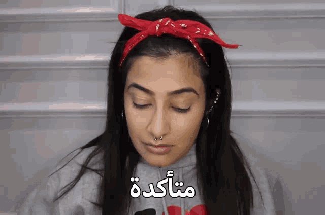 a woman wearing a red bandana and a gray sweatshirt has the word mitakade written on her face