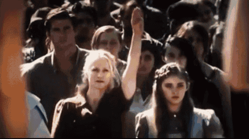 a group of people are standing in a crowd with one woman raising her fist in the air .
