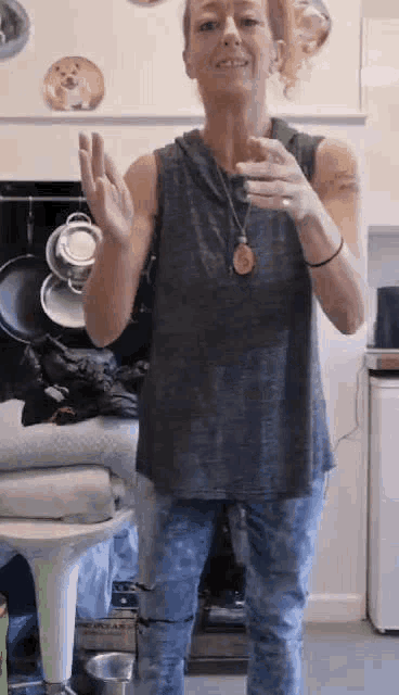 a woman is standing in a kitchen holding a glass of water and smiling .