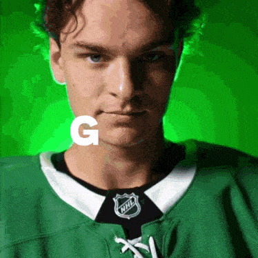 a man wearing a green nhl jersey with the letter g behind him