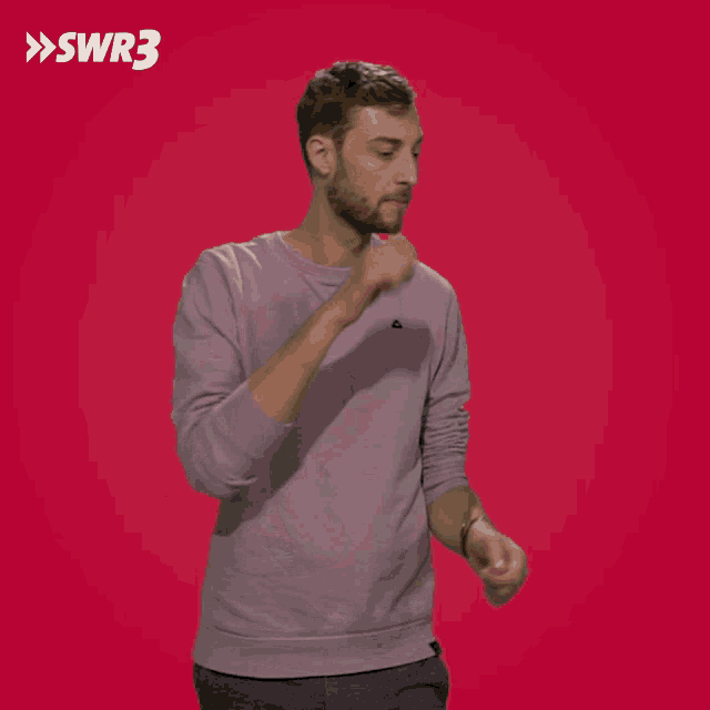 a man in a purple sweater stands in front of a red background with swr3 written on it