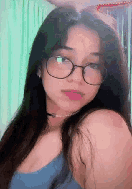 a woman wearing glasses and a choker is taking a selfie .