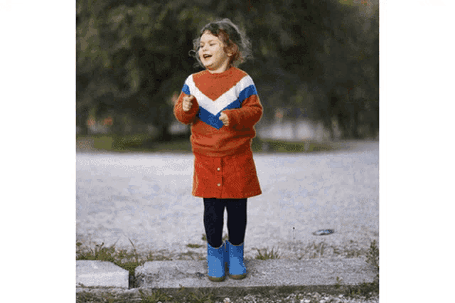 a little girl wearing a red white and blue sweater and skirt