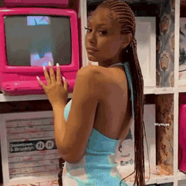 a woman in a blue dress stands in front of a pink computer monitor .