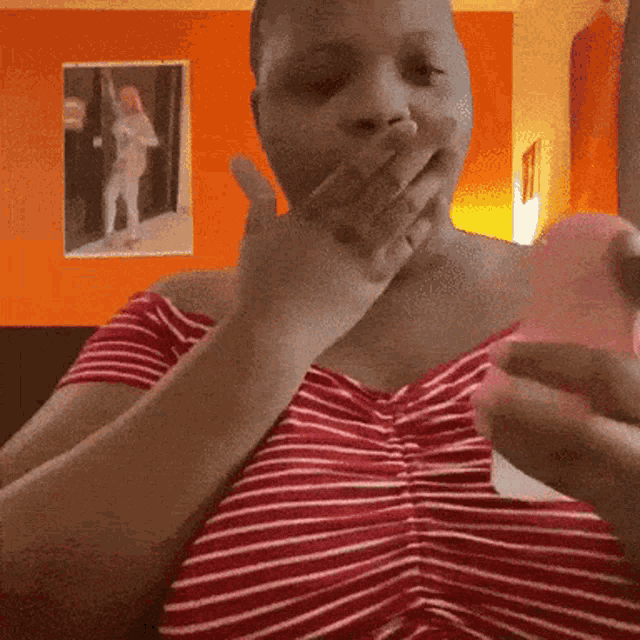 a woman in a red and white striped shirt is covering her mouth