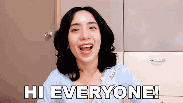 a woman says hi everyone in front of a cabinet
