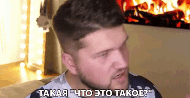 a man with a beard is talking in front of a fireplace in a foreign language