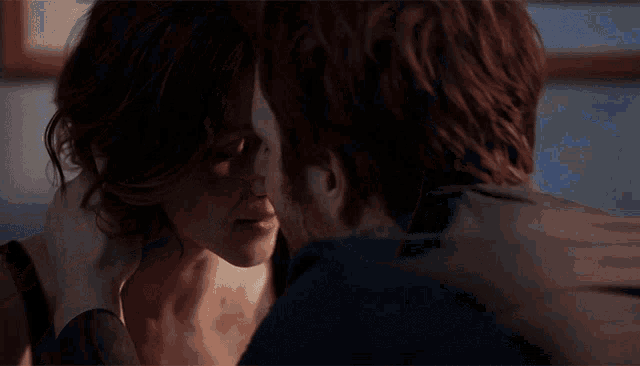 a man and woman are kissing in front of a blue background
