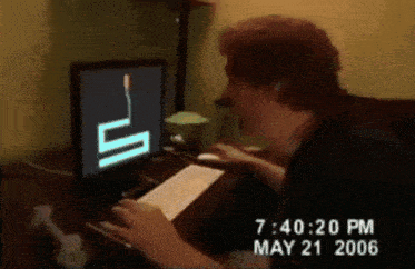 a man is typing on a keyboard in front of a computer monitor that says 7:40:20 pm may 21 2006