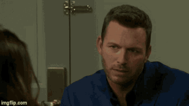 a man in a blue shirt is looking at a woman in front of a door ..