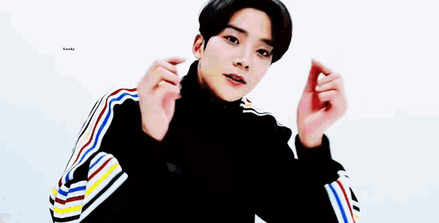 a young man is making a heart shape with his finger